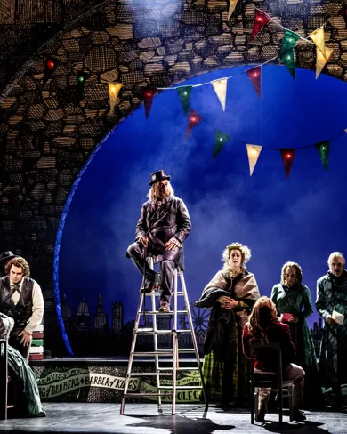 A group of people on a stage, one man sitting on a ladder.