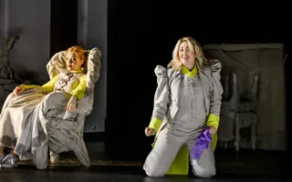 En kvinna sitter i en fåtölj, en man knäböjer vid sidan om henne.