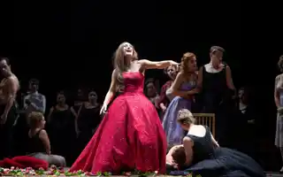 A woman in a red evening dress laughs and points her finger.