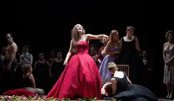 En kvinna i en röd aftonklänning skrattar och pekar finger.