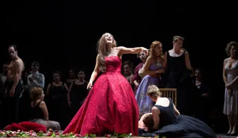 En kvinna i en röd aftonklänning skrattar och pekar finger.