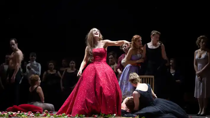 En kvinna i en röd aftonklänning skrattar och pekar finger.