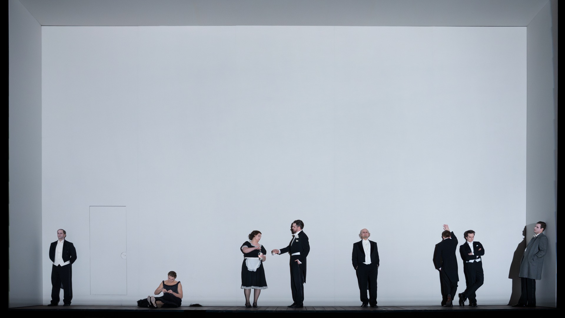 People dressed in black on stage with a white backdrop.