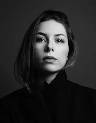 Närbild på en kvinna med mörkt hår som bär en mörk jacka.