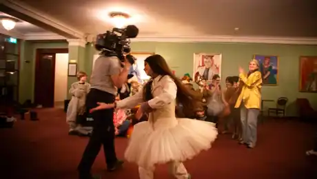 A child in a tutu dancing in front of a camera.
