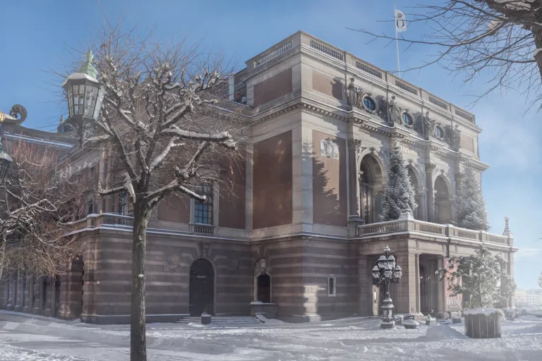 En stor byggnad mot en klarblå vinterhimmel, snö framför och på träd intill.