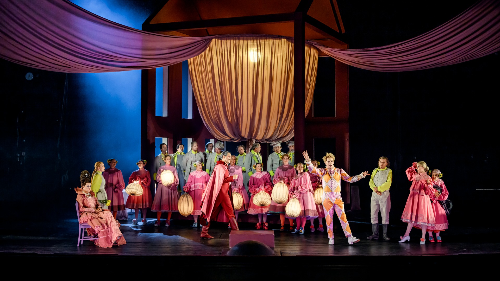 En samling under en baldakin på en scen - flera personer bär lyktor.