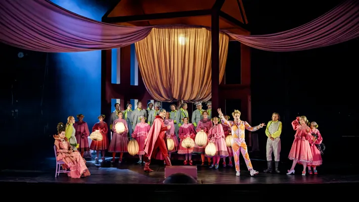 En samling under en baldakin på en scen - flera personer bär lyktor.