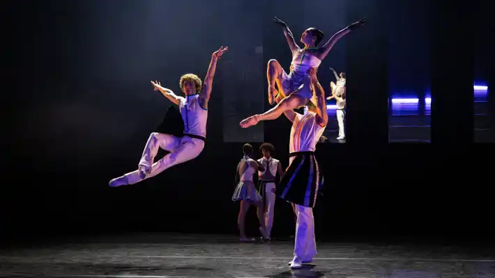 På en scen hoppar en dansare, en annan dansare lyfter en en kvinnlig dito.