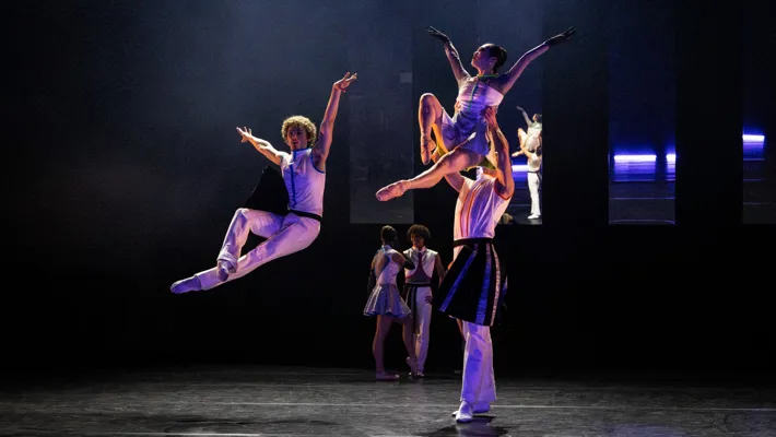 På en scen hoppar en dansare, en annan dansare lyfter en en kvinnlig dito.