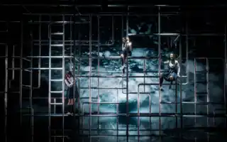 Mot en vattenfond syns en mängd rör: i rören klättrar tre kvinnor.