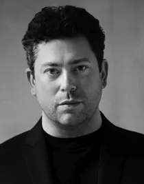 En närbild på en mörkhårig man i mörk kostym.