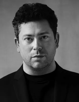 En närbild på en mörkhårig man i mörk kostym.