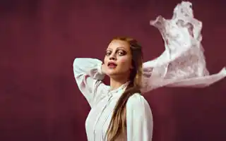 A woman with long hair wearing a white blouse.