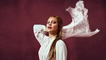 En kvinna med långt hår som bär en vit blus.