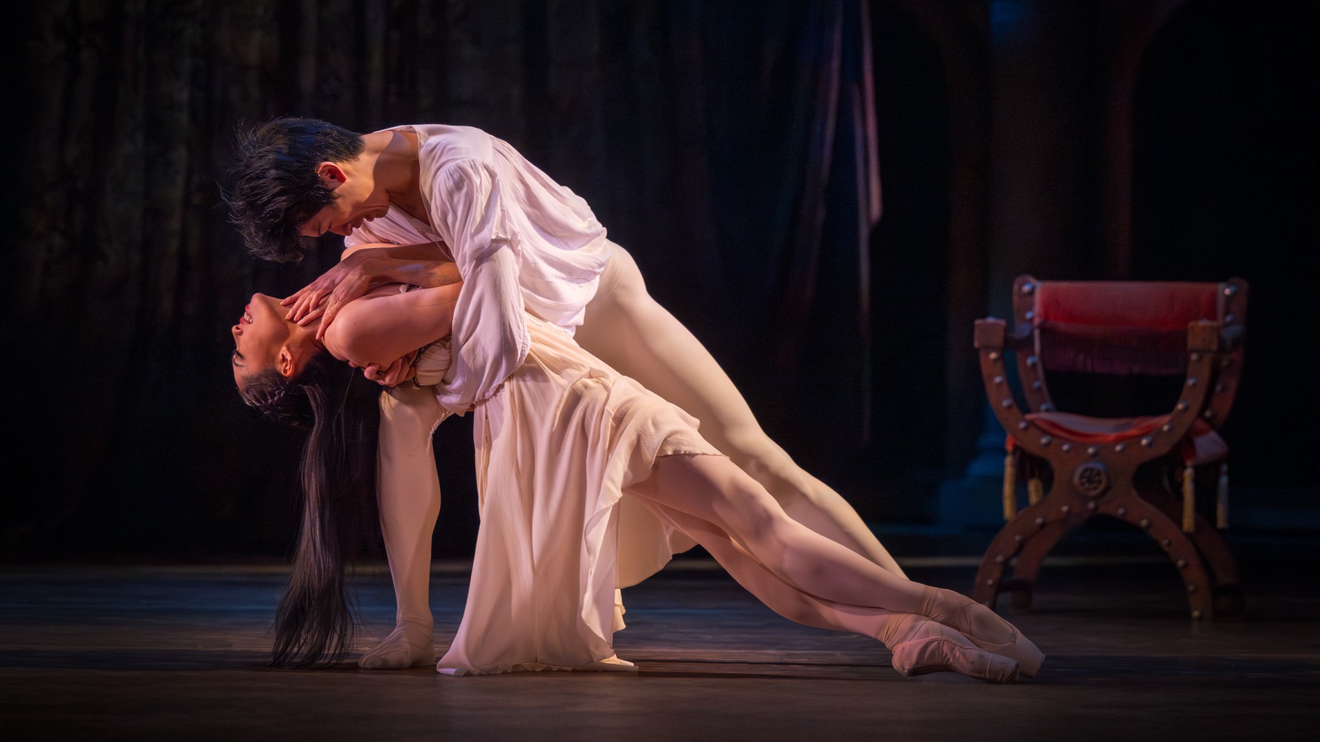 Två dansare, en man och en kvinna, i en öm rörelse där han håller henne i sina armar.