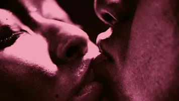 An extreme close-up of a kissing couple, only parts of their faces visible.