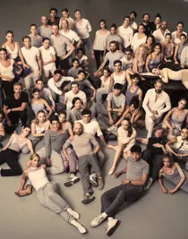 A large group of people sitting and standing, gathered in a cluster.