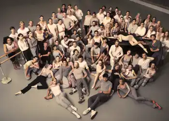 A large group of people sitting and standing, gathered in a cluster.