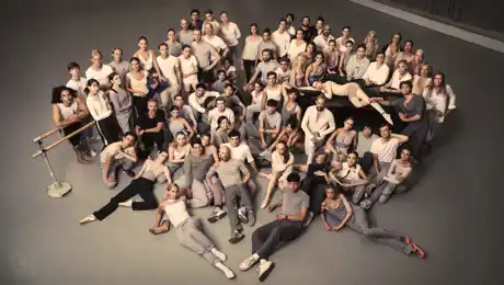 A large group of people sitting and standing, gathered in a cluster.