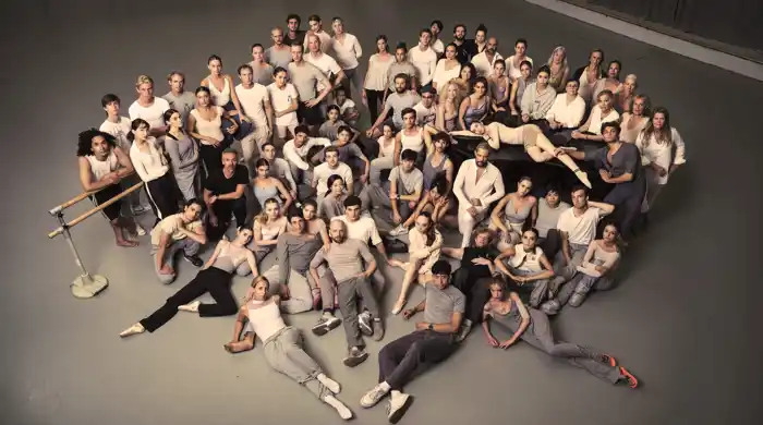 A large group of people sitting and standing, gathered in a cluster.