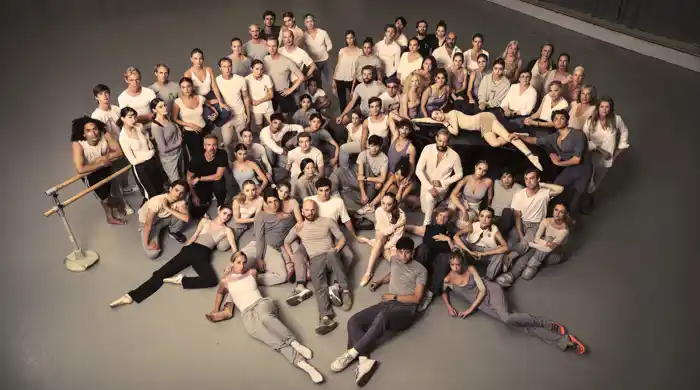 A large group of people sitting and standing, gathered in a cluster.
