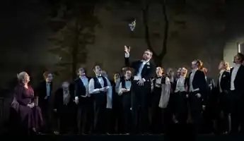 En man framför en grupp människor på scen.