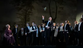 En man framför en grupp människor på scen.