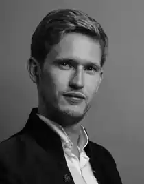 En närbild på en ljushårig man med vit skjorta och mörk kavaj.