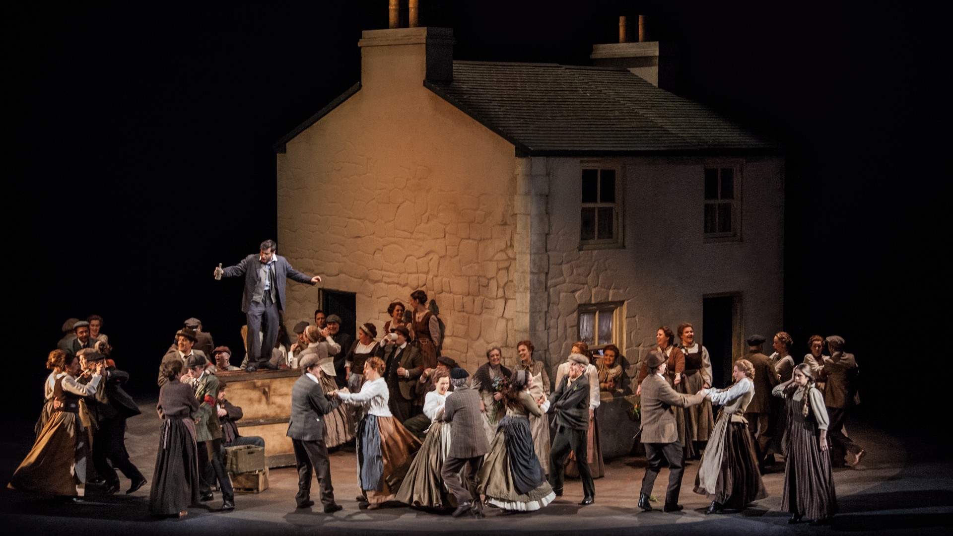 A scene with a large white house and a crowd of people in the foreground dancing.