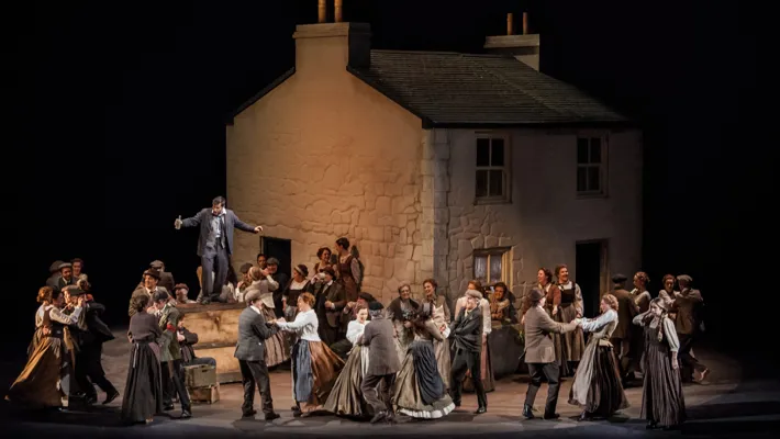 A scene with a large white house and a crowd of people in the foreground dancing.