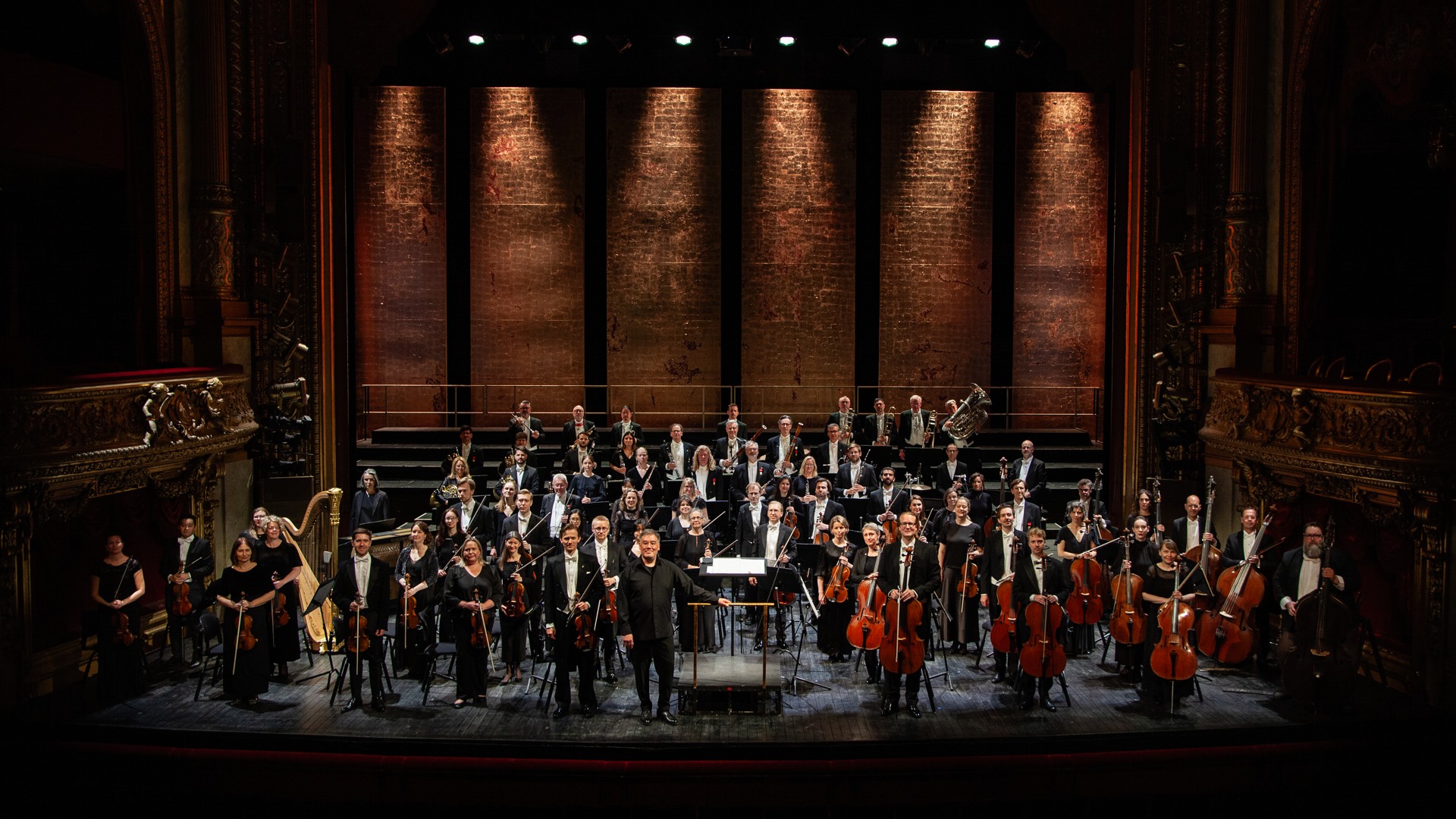 Många musiker står utspridda på en stor scen.