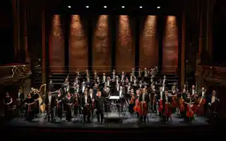 Många musiker står utspridda på en stor scen.