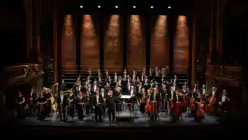 Många musiker står utspridda på en stor scen.