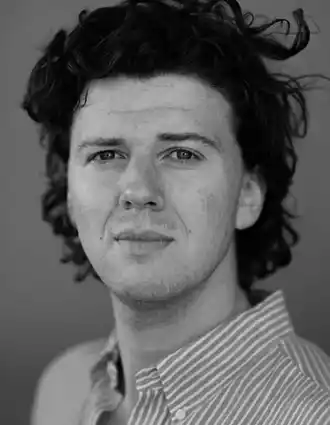 Close-up of a man with bushy hair and a striped shirt.
