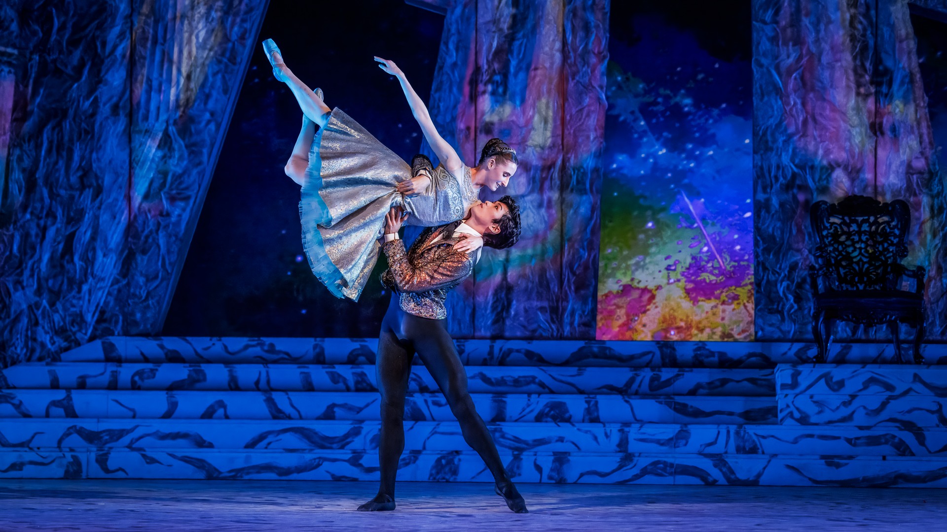 En manlig dansare lyfter en kvinnlig dansare högt.