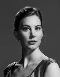 Närbild på en kvinna med uppsatt hår, hon bär ett ärmlöst liv i siden.