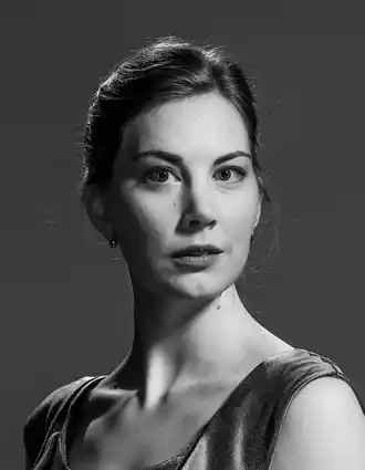 Close-up of a woman with her hair up, she is wearing a sleeveless silk top.