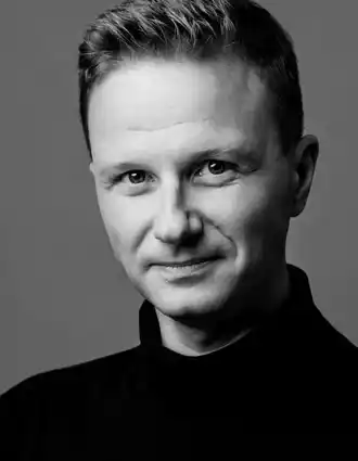 Närbild på en blond man med mörk polotröja.