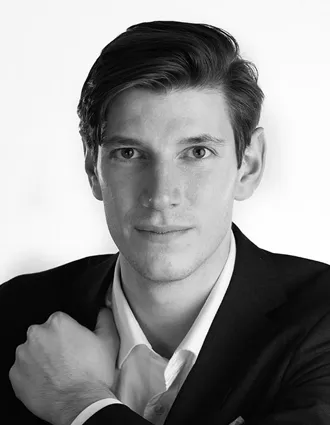 En närbild på en man klädd i vit skjorta och mörk kavaj.