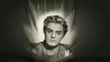 En svart-bild porträttbild av en man i kostym, bakom honom ljuslågor.