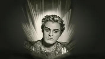 A black-and-white portrait image of a man in a suit, behind him candle flames.