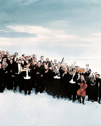 En samling personer i svarta kostymer, några med instrument, står i ett vinterslandskap.