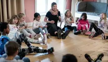 Pedagog med barn i en ring som gör musikaliska övningar.