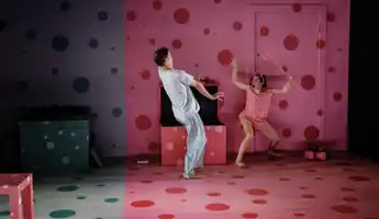 En flicka med en treudd och djävulshorn skrämmer en pojke på en scen.