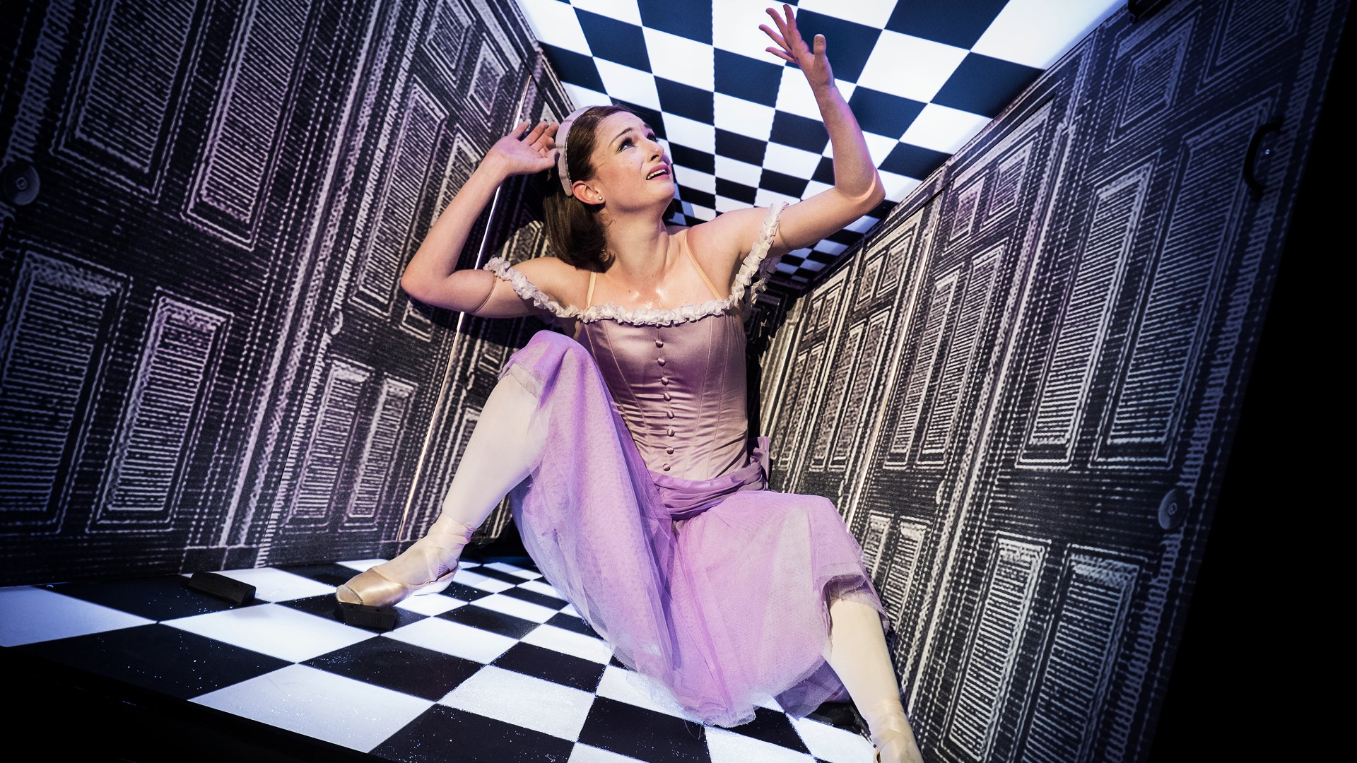 En kvinna i en lila klänning sitter på ett rutigt golv.