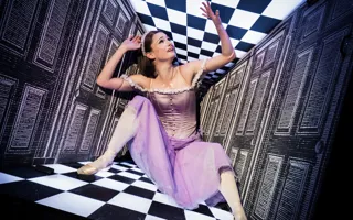 En kvinna i en lila klänning sitter på ett rutigt golv.