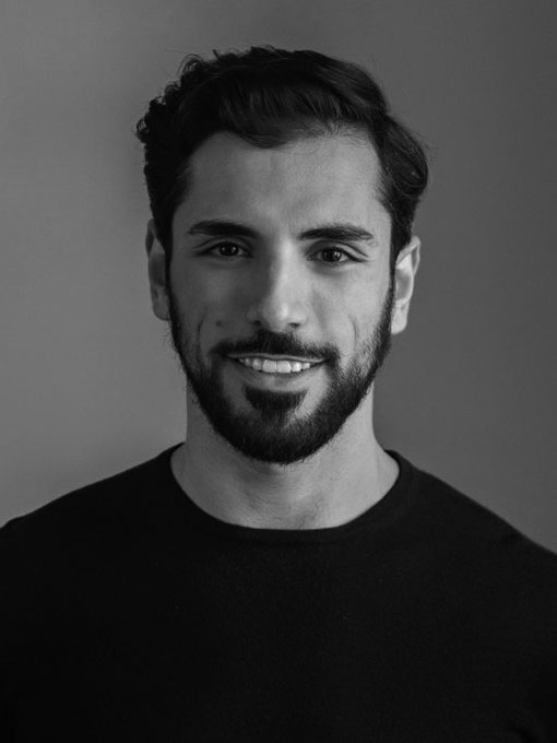 Portrait image of a smiling dark-haired man with a beard, wearing a dark shirt.