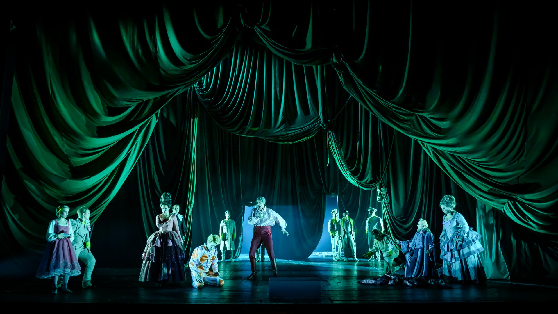 En grupp människor på en scen, omgivna av ett tungt grönt draperi.