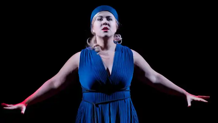 A woman in blue clothes stretches her arms out.